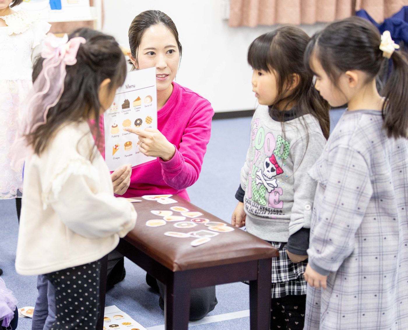 床に並べたアルファベットのカードで遊ぶ子どもたち